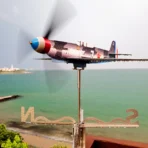 Stainless steel Yak9 weathervane and wind spinner in motion after rain against sea