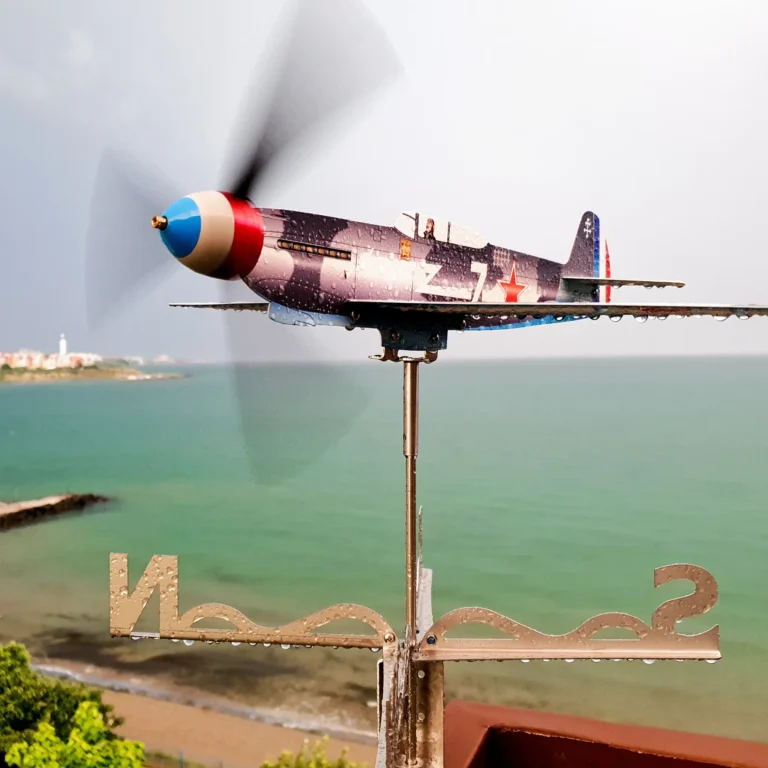 Stainless steel Yak9 weathervane and wind spinner in motion after rain against sea