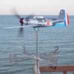 Yak9 kinetic wind sculpture and weathervane of corrosion resistant stainless steel spinning on a seaside terrace