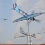 Yak9 stainless steel weathervane and wind spinner outdoors with a seagull flying in the background