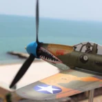 Close up of a coastal resistant steel P39 fighter aircraft model wind spinner against a blurry sea backdrop