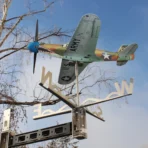 Stainless steel P39 aircraft weathervane with extension arm serves as landmark and stand for outdoor advertising