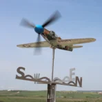 Stainless Steel P39 fighter aircraft model functioning as a garden weathervane in an open landscape environment